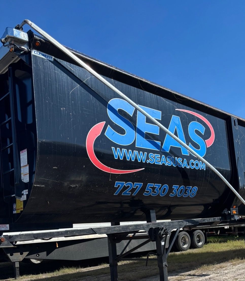 Black dump trailer with large blue and red vinyl logo and lettering before removal
